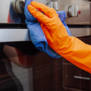 Hand with a microfiber cloth is being wiped on the outside of the electric oven.